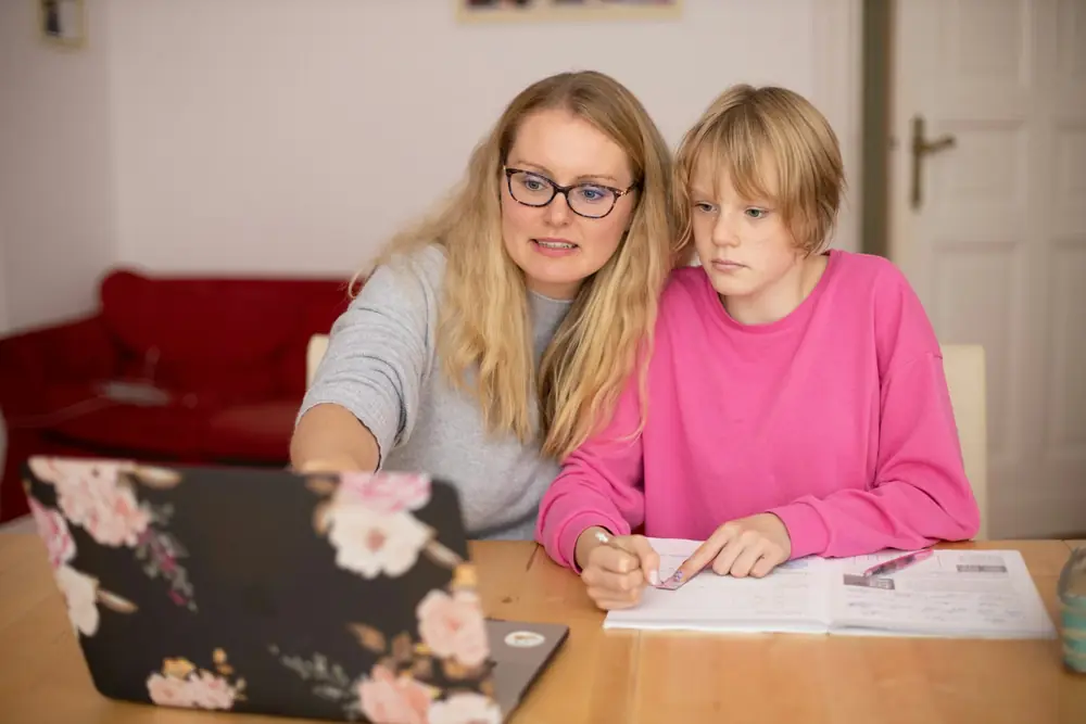 A parent and teenager looking at schoolwork together at home