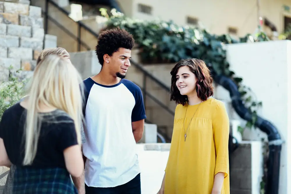 Three young people talking and laughing outside a building